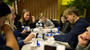 Kinder arbeiten gemeinsam an einem Roboter-Projekt in einem sommerlichen Ferienkurs.