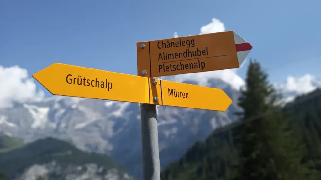 Wegweiser für Wanderer vor einer beeindruckenden Bergkulisse in den Alpen.
