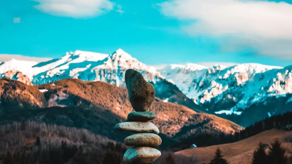 Ein Steinturm vor einer beeindruckenden, schneebedeckten Bergkulisse in der Natur.