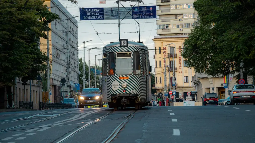 Eine historische Straßenbahn fährt in der Dämmerung durch eine belebte europäische Stadtstraße.