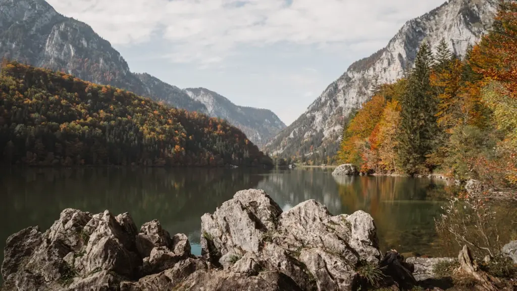 Bergsee umgeben von herbstlichen Bäumen und hohen Bergen in Österreich.
