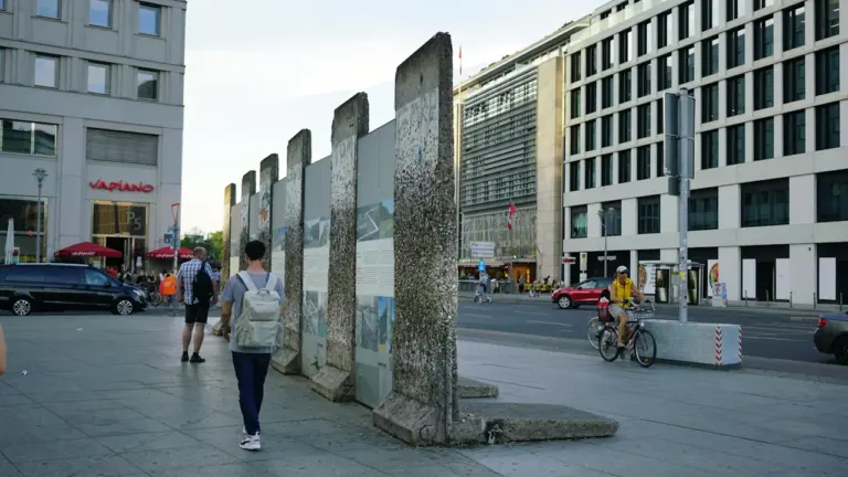 Menschen spazieren an einem erhaltenen Stück der Berliner Mauer im Stadtzentrum von Berlin.