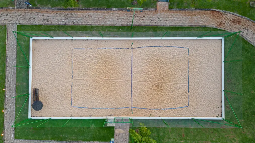 Luftaufnahme eines leeren Beach-Tennis-Platzes mit Sandbelag in einer modernen Sportanlage.