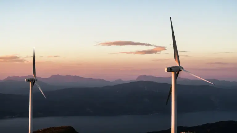 Zwei moderne Windkraftanlagen vor einer malerischen Hügellandschaft bei Sonnenuntergang in Norddeutschland.
