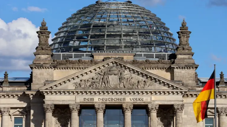 Das Reichstagsgebäude mit der gläsernen Kuppel und der wehenden deutschen Flagge in Berlin.