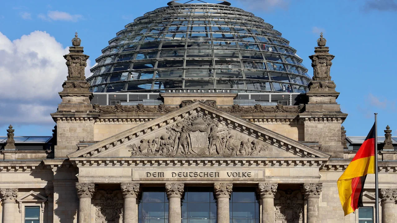 Das Reichstagsgebäude mit der gläsernen Kuppel und der wehenden deutschen Flagge in Berlin.