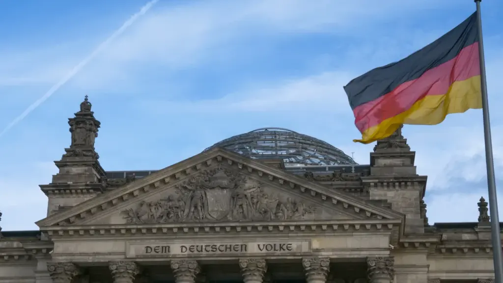 Die deutsche Flagge weht vor dem Reichstagsgebäude in Berlin bei strahlend blauem Himmel.
