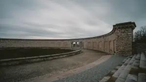 Die Gedenkstätte Buchenwald mit der markanten geschwungenen Mauer unter einem bewölkten Himmel.