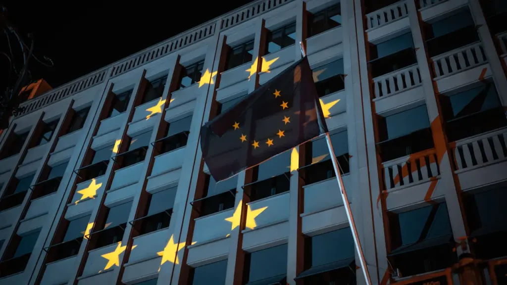 Die Europafahne weht vor einem beleuchteten EU-Gebäude in Berlin bei Nacht.