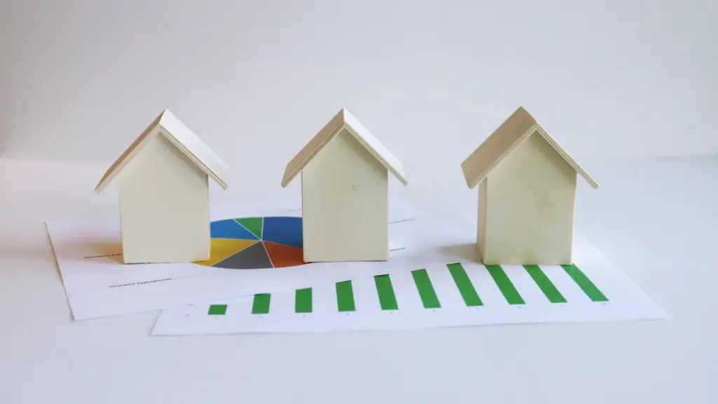 Drei kleine Modellhäuser auf einer Grafik mit steigendem grünem Balkendiagramm und Tortendiagramm.