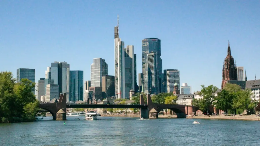 Moderne Frankfurter Skyline mit dem Main Fluss, einer historischen Brücke und Kirchturm.