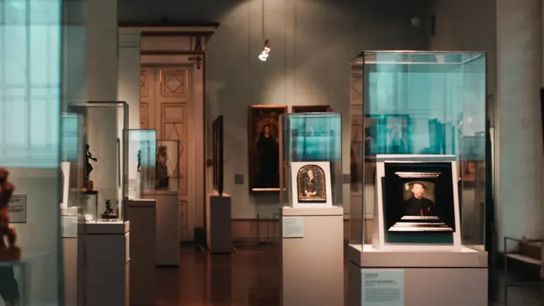 Museumsausstellung mit zahlreichen Glaskästen und Kunstwerken in einem eleganten, atmosphärischen Raum.