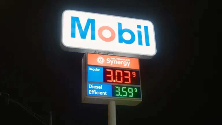 Eine beleuchtete Preistafel an einer Tankstelle in der dunklen Nacht.