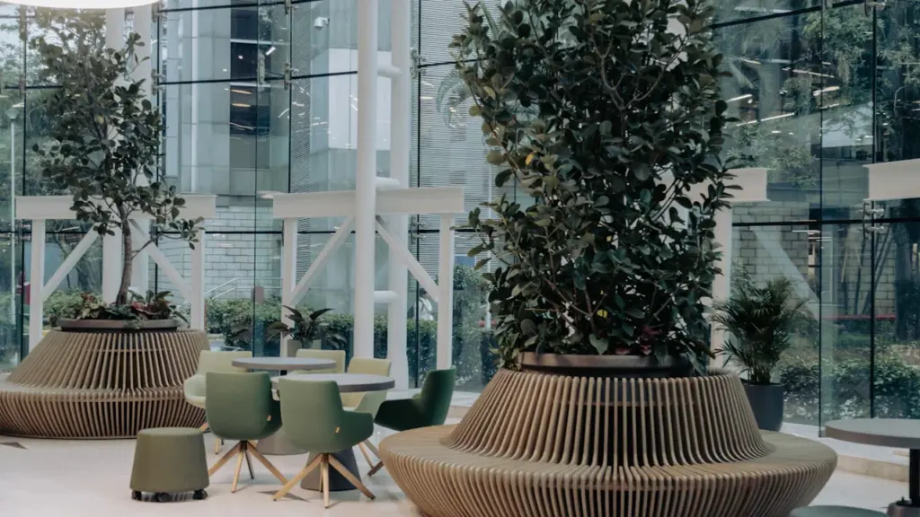 Helle, moderne Bürolobby mit großen Glasfronten, Pflanzen und organischen Sitzmöbeln für ein ruhiges Arbeitsumfeld.