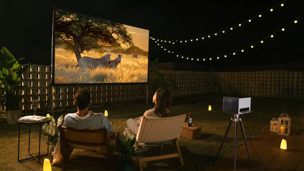 Ein Paar genießt abends einen Film bei einem Open-Air-Kino im privaten Garten.