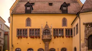 Historisches gelbes Gebäude mit kunstvollem Erker am Bismarckplatz in Regensburg bei Tageslicht.