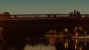 Stimmungsvolle beleuchtete Brücke über einem Fluss in der blauen Stunde am Abend.