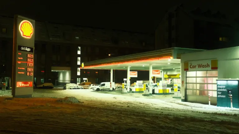 Eine beleuchtete Shell-Tankstelle in der Nacht bei winterlichem Wetter und Schnee.