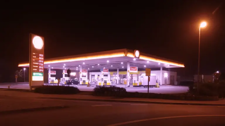 Eine beleuchtete Tankstelle bei Nacht mit gut sichtbarer Preistafel für Benzin und Diesel.