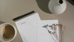 Ein offener Planer auf einem Tisch mit einer Tasse Kaffee und Büroklammern.