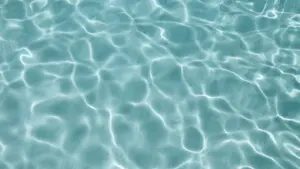 Klarer, sonnenbeschienener Wasserspiegel mit sanften, sich bewegenden Wellen im hellen Tageslicht.