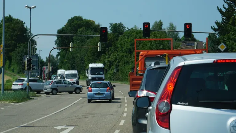 Autoverkehr an einer Ampelkreuzung auf einer deutschen Landstraße am Tag.