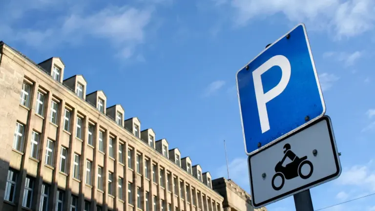 Ein blaues Parkschild vor einem großen, traditionellen Gebäude in einer deutschen Stadt.