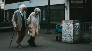 Ein älteres Ehepaar geht gemeinsam langsam durch eine deutsche Innenstadt.