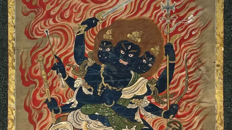 Ein blauhäutiges, dreiköpfiges buddhistisches Gottheitsbild mit vielen Armen vor einem Hintergrund aus Flammen.