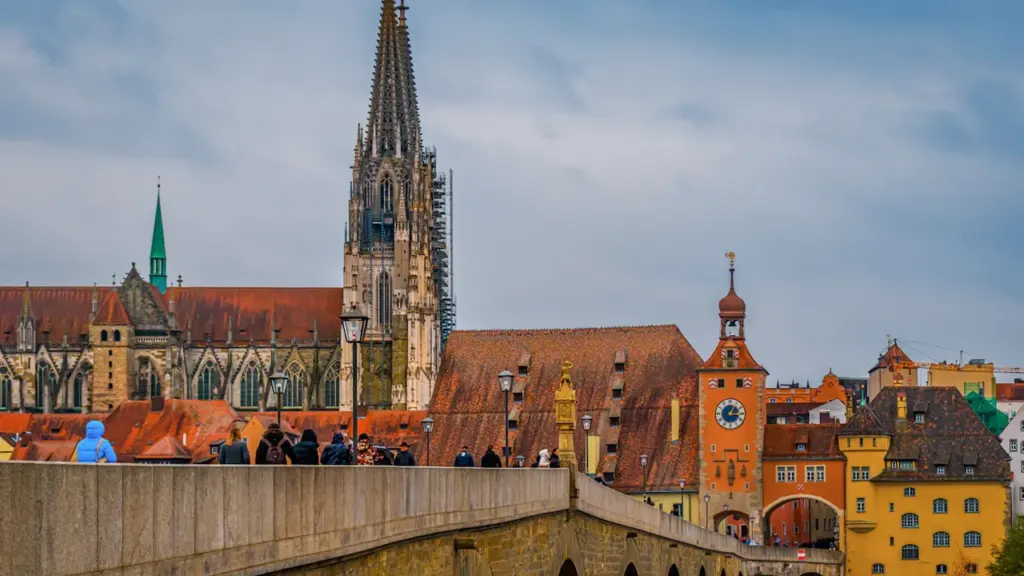 Historische Steinerne Brücke vor dem Regensburger Dom bei bewölktem Tageslicht.