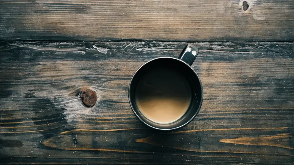 Draufsicht auf eine Kaffeetasse auf einem rustikalen, dunklen Holztisch in Regensburg.