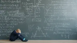 Ein erschöpftes Kind sitzt vor einer mit mathematischen Formeln beschriebenen Tafel auf dem Boden.